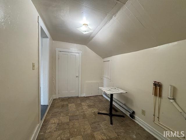 additional living space with dark tile patterned flooring and lofted ceiling