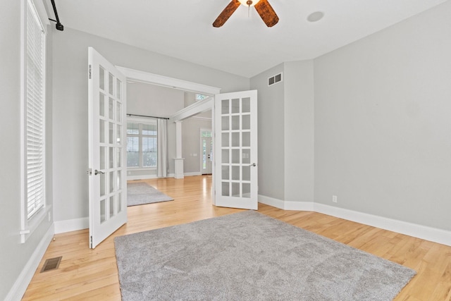 unfurnished room featuring wood finished floors, french doors, a ceiling fan, visible vents, and baseboards