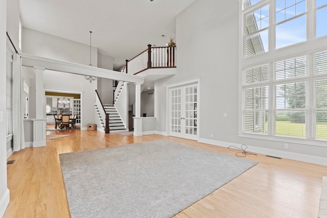 unfurnished living room featuring stairs, a high ceiling, a notable chandelier, and wood finished floors