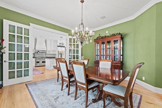 dining room featuring crown molding, a notable chandelier, baseboards, and light wood-style floors