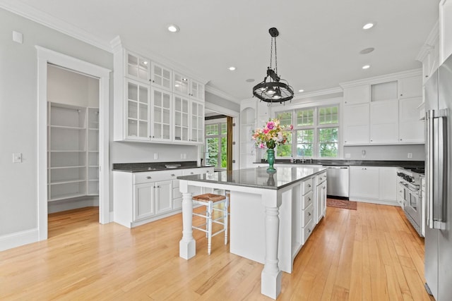 kitchen with ornamental molding, dark countertops, stainless steel appliances, and white cabinets