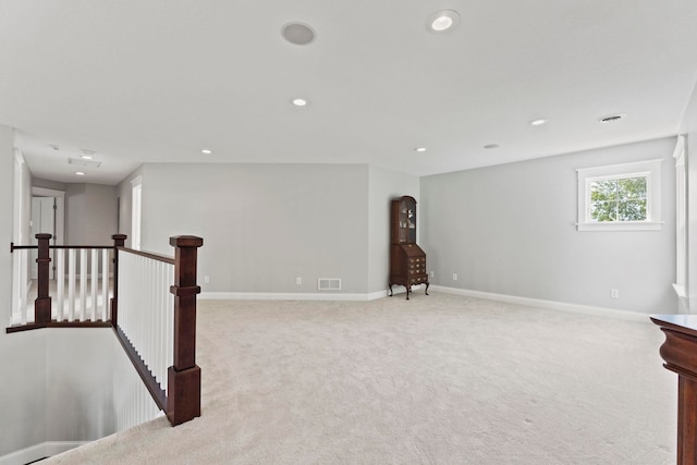 unfurnished room with light colored carpet, baseboards, an upstairs landing, and recessed lighting
