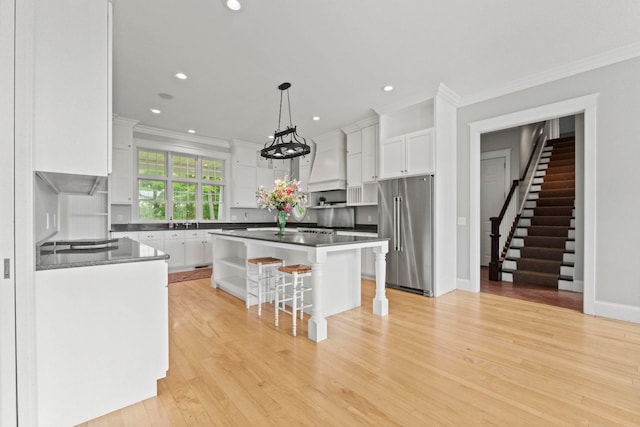 kitchen with crown molding, white cabinetry, a kitchen bar, high end refrigerator, and a kitchen island
