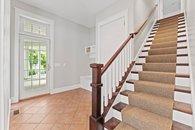 entryway with stairway, light tile patterned flooring, baseboards, and visible vents