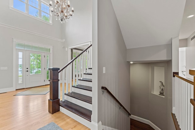 foyer entrance with wood finished floors, a towering ceiling, and a healthy amount of sunlight