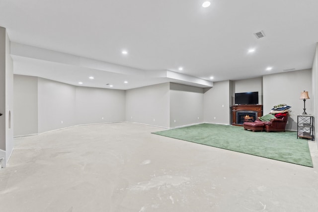 finished basement with baseboards, visible vents, recessed lighting, and a lit fireplace