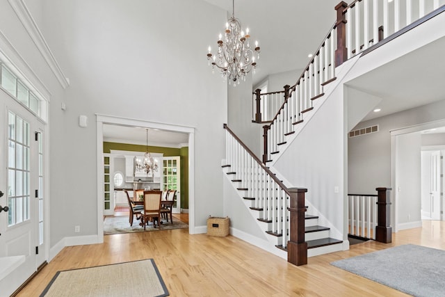 foyer entrance with wood finished floors, a high ceiling, baseboards, a chandelier, and stairs