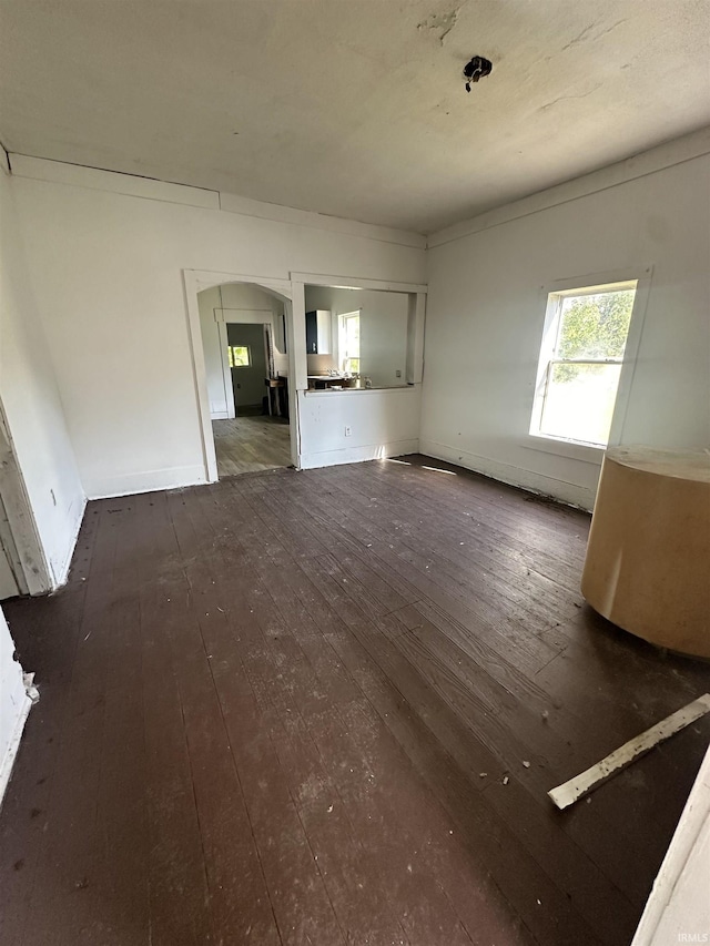 unfurnished living room featuring dark wood finished floors and baseboards