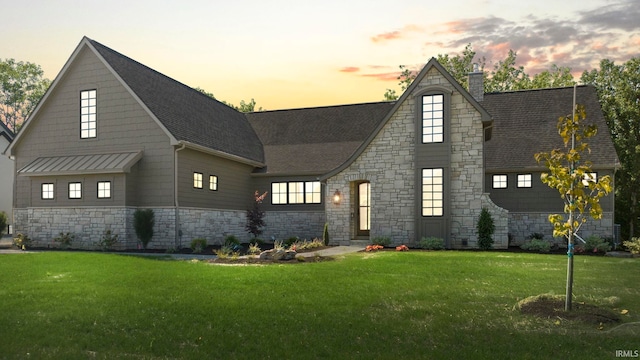 view of front of property with a shingled roof, metal roof, a chimney, and a front lawn