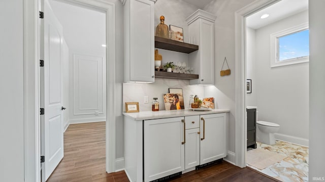 bar featuring decorative backsplash, hardwood / wood-style floors, and white cabinetry