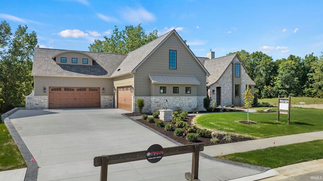 view of front of home featuring a shingled roof, concrete driveway, an attached garage, a front yard, and stone siding