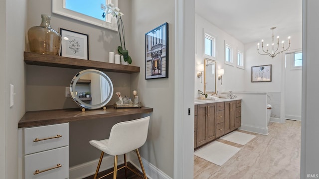 bathroom with wood finished floors, an inviting chandelier, baseboards, and double vanity