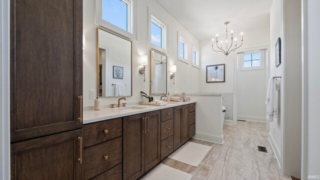 bathroom featuring hardwood / wood-style floors, an inviting chandelier, and vanity