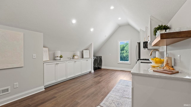 kitchen with washing machine and dryer, dark wood-type flooring, stainless steel fridge, and lofted ceiling