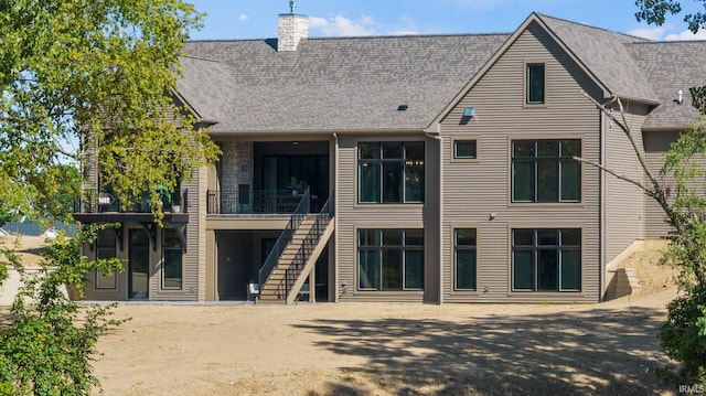 rear view of property with a chimney and stairway