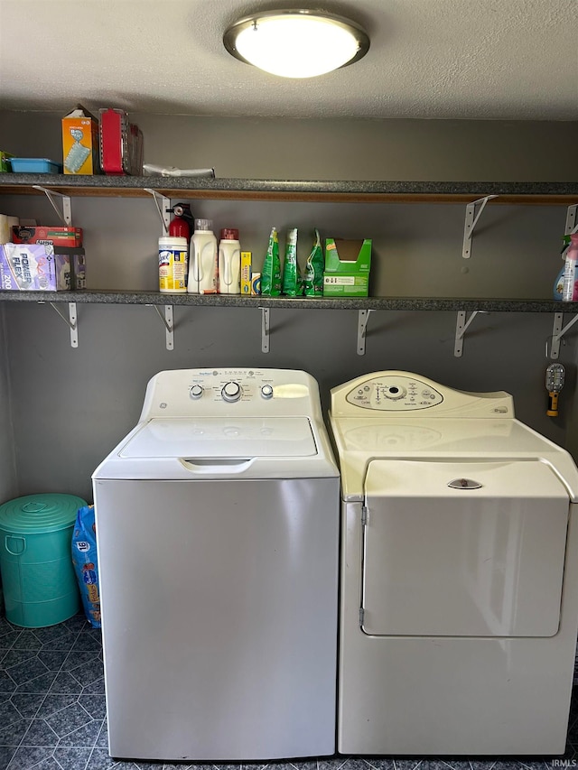 washroom featuring a textured ceiling, separate washer and dryer, and dark tile patterned flooring