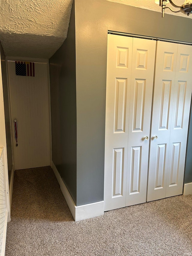 hall with a textured ceiling and carpet floors