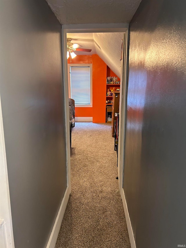 corridor featuring lofted ceiling, a textured ceiling, and carpet floors