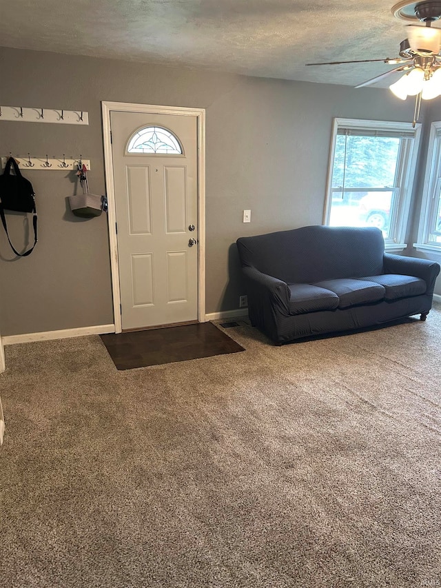 carpeted foyer entrance featuring a textured ceiling and ceiling fan