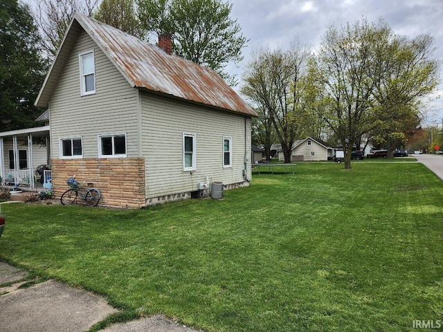 view of side of property with a lawn and central AC unit