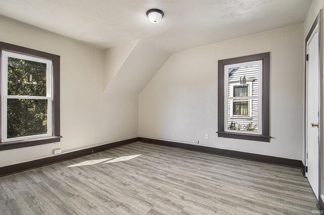 bonus room with lofted ceiling, plenty of natural light, and hardwood / wood-style floors