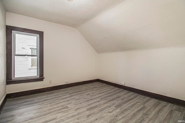 additional living space featuring lofted ceiling and hardwood / wood-style floors