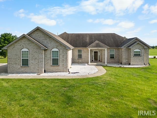 rear view of property featuring a lawn and brick siding