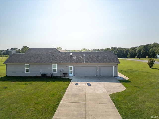 rear view of property featuring a lawn, a garage, and central AC