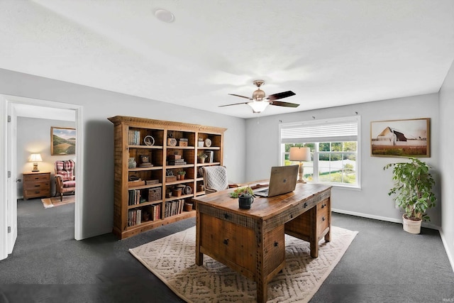 home office featuring dark carpet, baseboards, and a ceiling fan