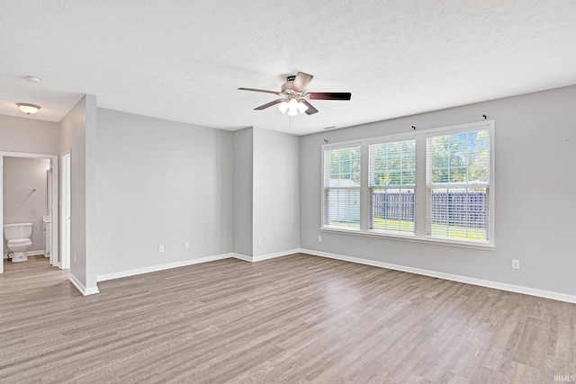 empty room with ceiling fan, light hardwood / wood-style flooring, and a textured ceiling