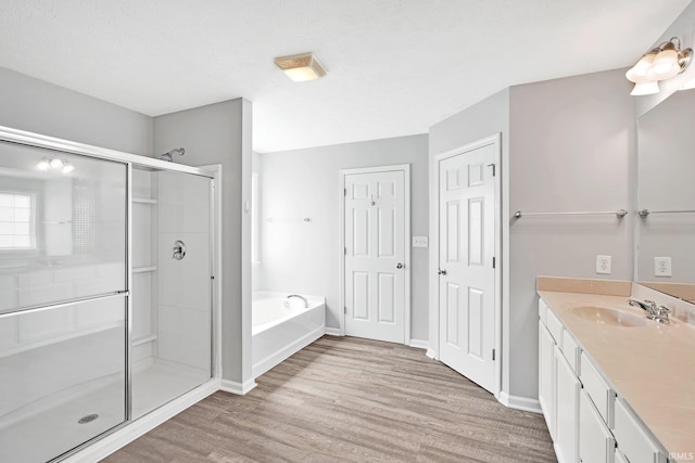 bathroom with vanity, wood finished floors, baseboards, a shower stall, and a bath