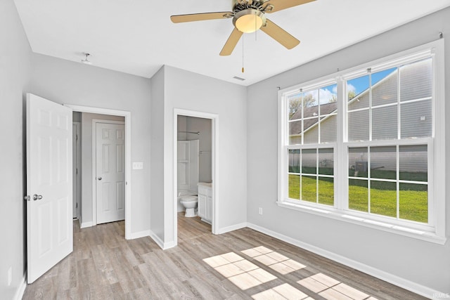 unfurnished bedroom featuring multiple windows, ensuite bathroom, and light hardwood / wood-style flooring