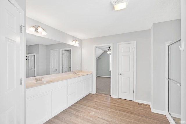 bathroom with a sink, baseboards, wood finished floors, and double vanity