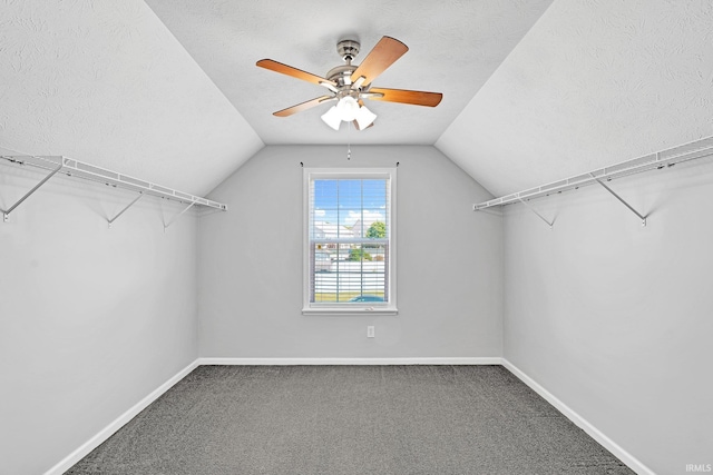 spacious closet with vaulted ceiling, carpet floors, and ceiling fan