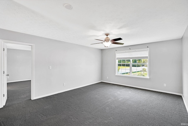 empty room featuring ceiling fan, dark carpet, and a textured ceiling