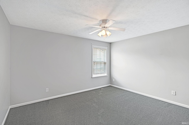 spare room with a ceiling fan, visible vents, baseboards, a textured ceiling, and dark colored carpet