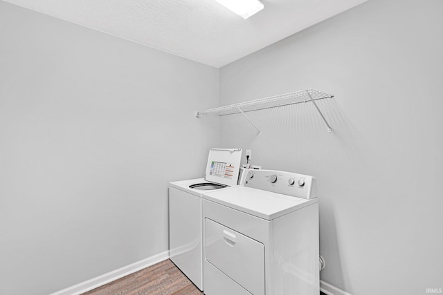 washroom with laundry area, independent washer and dryer, light wood-style flooring, and baseboards