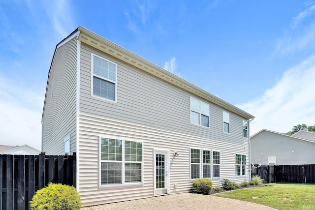 back of property with a patio, a lawn, and fence