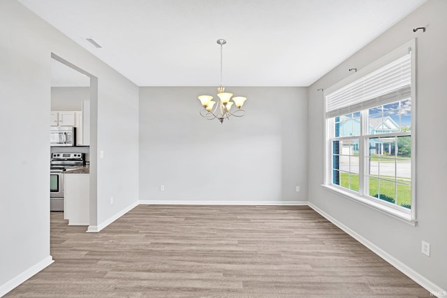 unfurnished room featuring an inviting chandelier and light hardwood / wood-style flooring