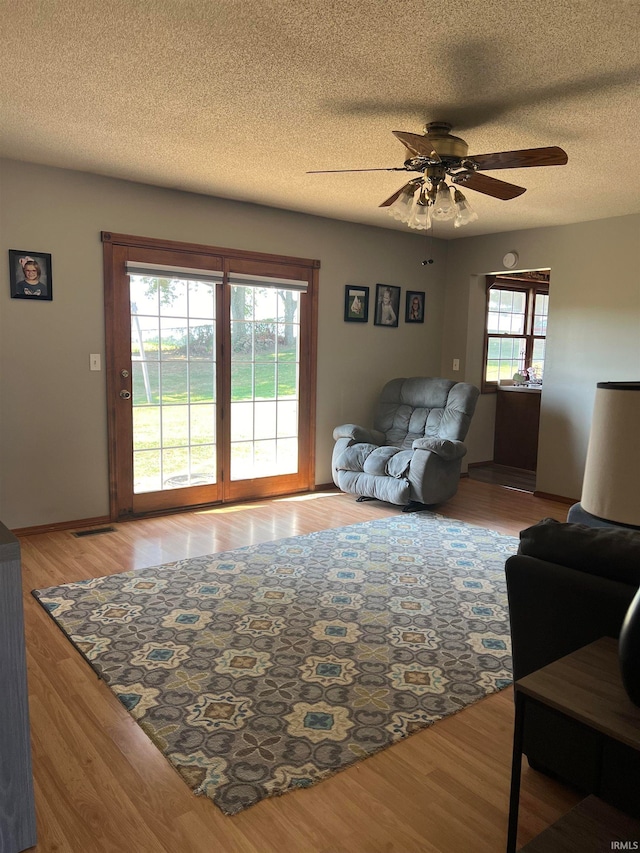 living room featuring a textured ceiling, ceiling fan, and hardwood / wood-style flooring