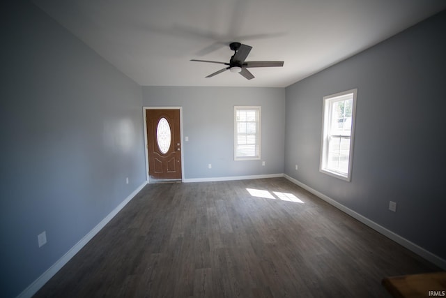 interior space with a ceiling fan, baseboards, and dark wood-style flooring