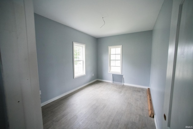 unfurnished room featuring wood finished floors, baseboards, and a baseboard radiator