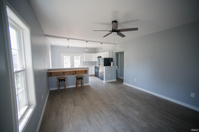 unfurnished living room with visible vents, baseboards, a ceiling fan, and dark wood-style flooring