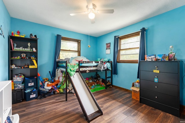 bedroom featuring ceiling fan, dark hardwood / wood-style flooring, and a textured ceiling