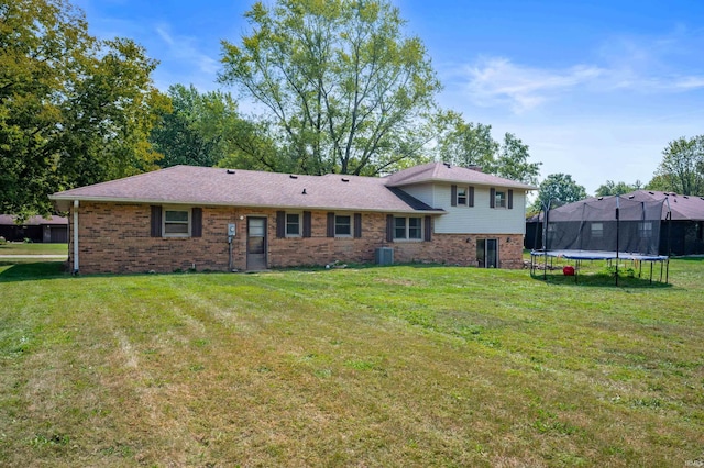 rear view of house featuring a trampoline, a lawn, and central AC unit