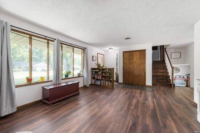 living room featuring a wealth of natural light, dark wood-type flooring, and a textured ceiling