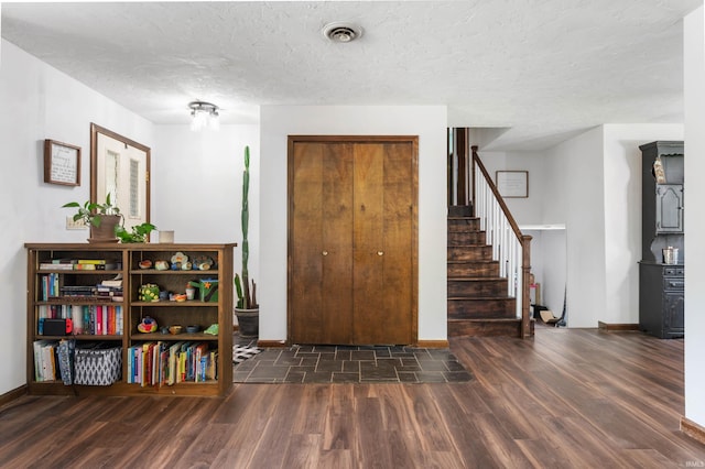 foyer entrance featuring a textured ceiling and dark hardwood / wood-style floors