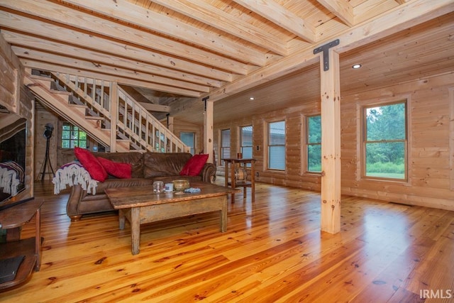 living room with wooden ceiling, hardwood / wood-style flooring, wooden walls, stairway, and beamed ceiling