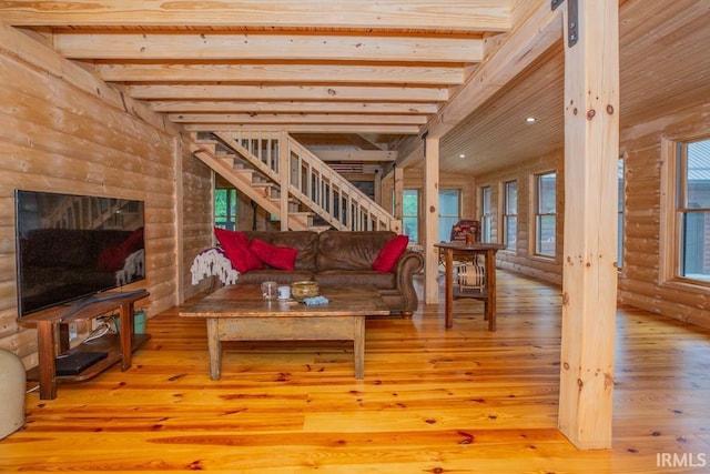 living area with light wood-style flooring, stairway, and log walls