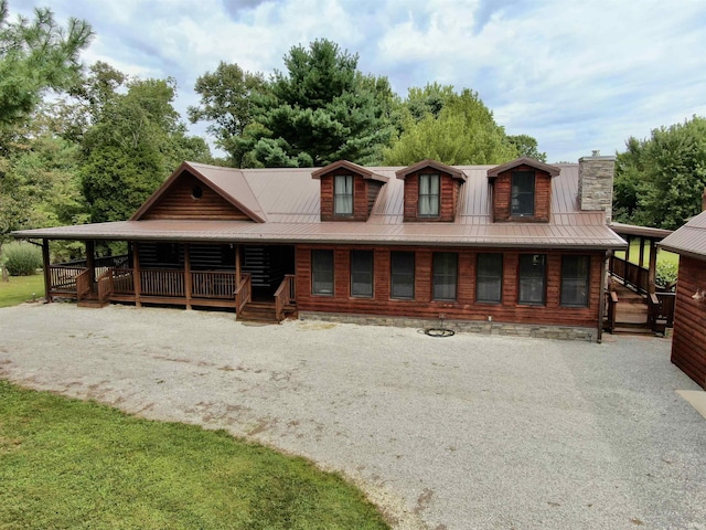 log home with driveway, a chimney, metal roof, and a porch